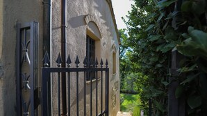 A building with a wrought iron gate, stone steps, and a garden with ivy. - Cammino Santo - studio w/private pool & garden (Poggibonsi)
