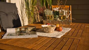 Una mesa de madera con un bol de galletas, dos manzanas y dos copas de vino blanco.