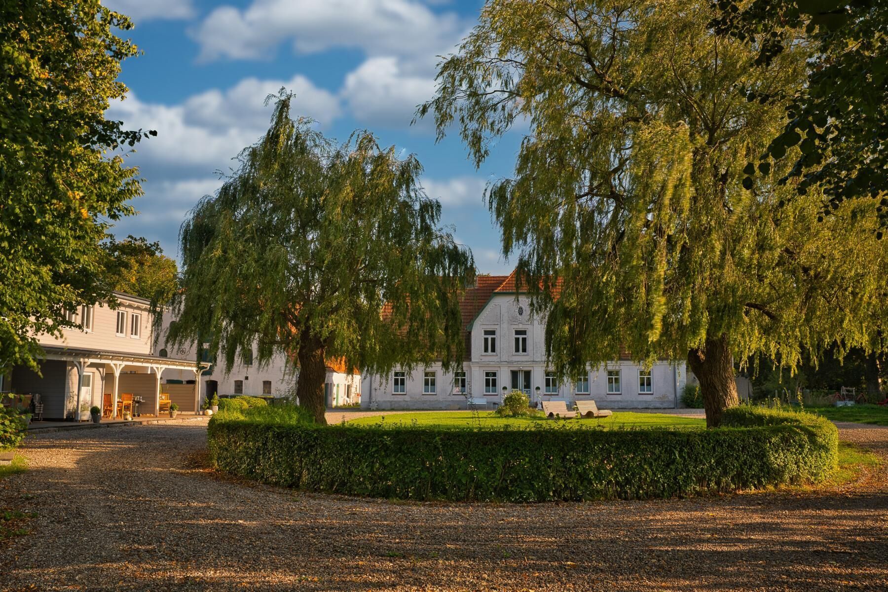 Historiallinen rakennus, jonka symmetrinen julkisivu on säilytetty, ja jota ympäröi hyvin hoidettu puutarha ja suuret, vanhat puut.