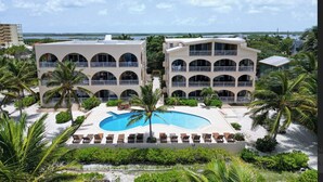 Un complexe hôtelier doté d’une piscine, de plusieurs balcons et de palmiers.