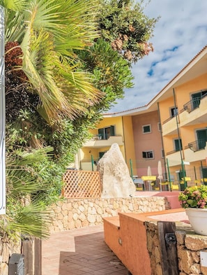 A sign for 'I Mirti Bianchi' reception with contact details and a view of a building with balconies and a stone wall. - Quaint Residence I Mirti Bianchi Bilo 4 no 6979 one Bedroom Apartments Sleeps 4 (Santa Teresa di Gallura)