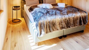 A wooden interior with a bed, a round table, and a hanging light fixture. - Pfänder Glück (Lochau)