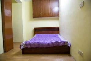 Cozy retreat with a single bed, wooden headboard, and a wardrobe above.