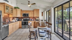 Una cocina moderna con armarios de madera, una isla grande y un comedor con sillas.
