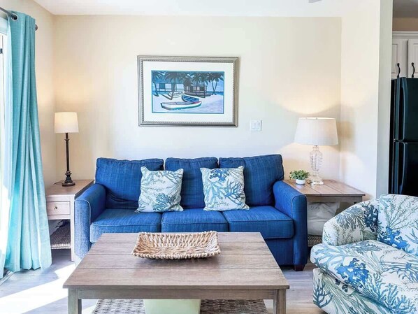 A living room with a blue sofa, a coffee table, and a framed picture on the wall.