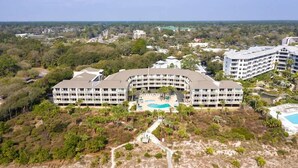A large hotel with a central pool, surrounded by greenery and other buildings. - Luxury Oceanfront Villa, w/ Pool on Hilton Head (Hilton Head Island)