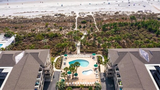 An aerial view of a resort with a central swimming pool, surrounded by palm trees and pathways leading to the beach. - Luxury Oceanfront Villa, w/ Pool on Hilton Head (Hilton Head Island)