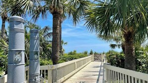 A wooden boardwalk with metal bollards, surrounded by palm trees and a clear sky. - Luxury Oceanfront Villa, w/ Pool on Hilton Head (Hilton Head Island)