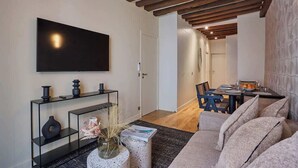 Een moderne woonkamer met een flatscreen televisie, een zwarte salontafel en een bank.