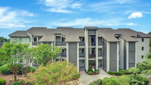 A multi-story residential building with balconies, a central courtyard, and surrounding greenery. - On the Sea Palms Golf Course. 18th Hole, Fairway and Lagoon frontage (Saint Simons Island)
