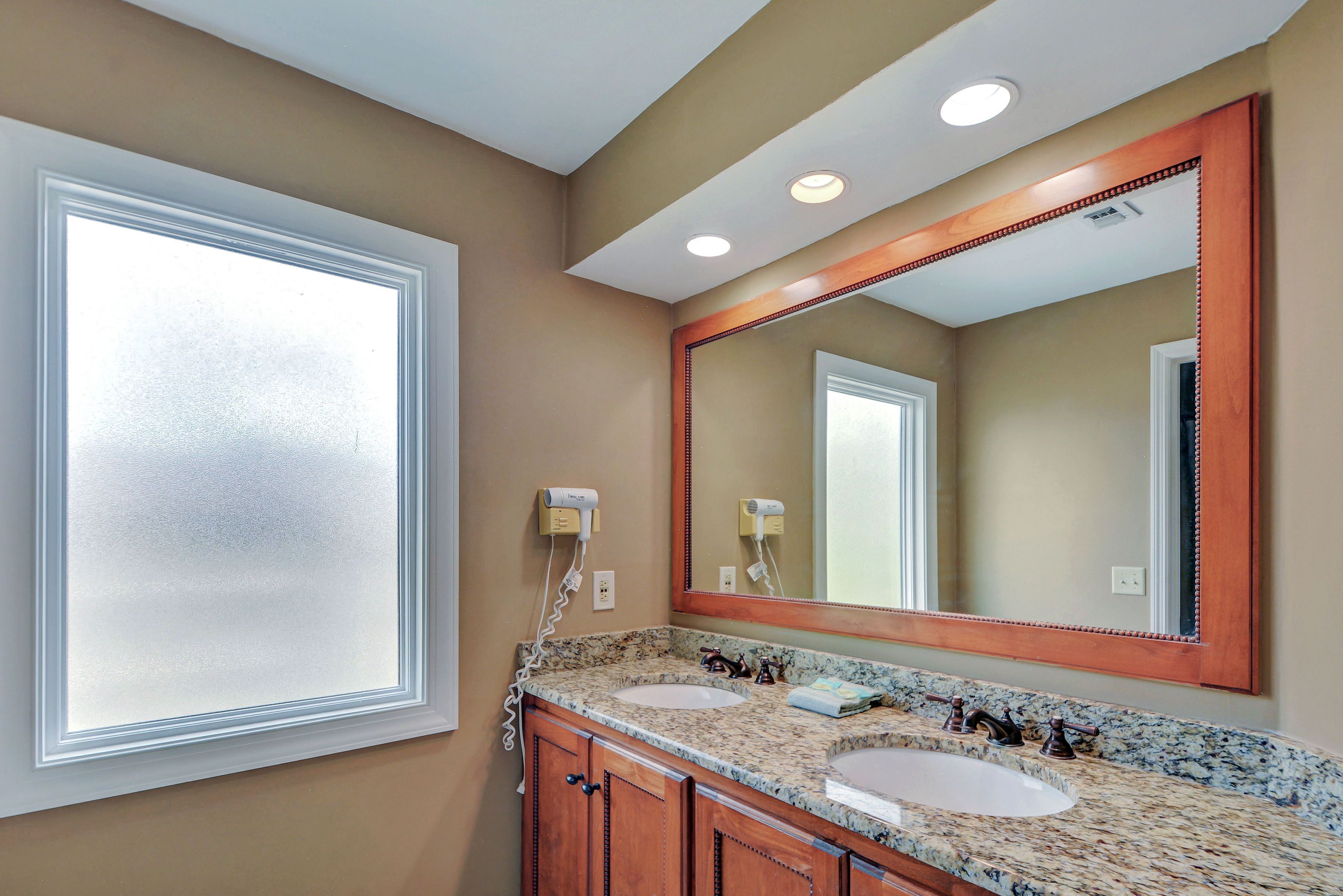 A bathroom with two sinks, a large mirror, and a window.