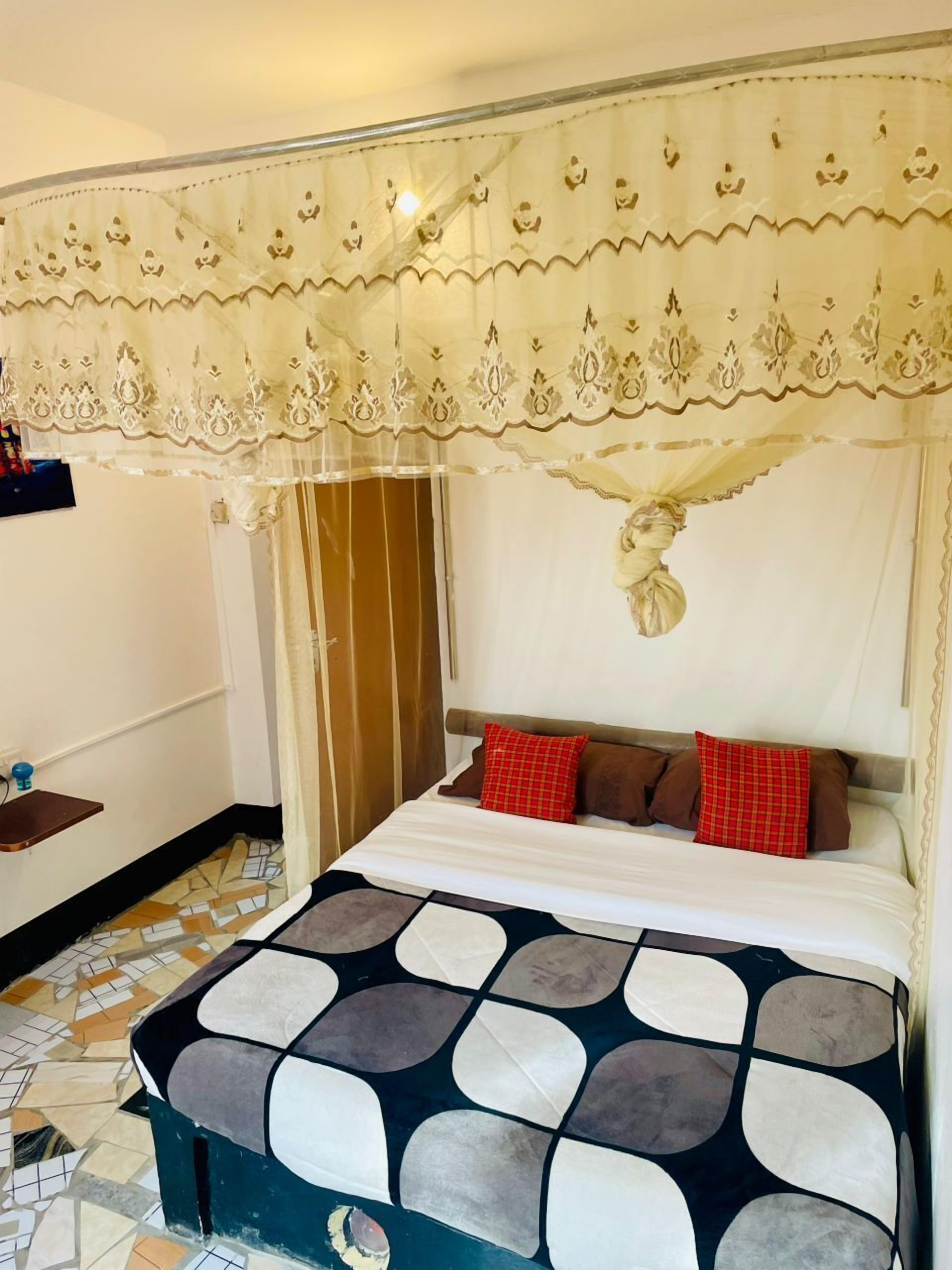 A bedroom with a bed, a canopy, a bedside table, and a patterned floor.