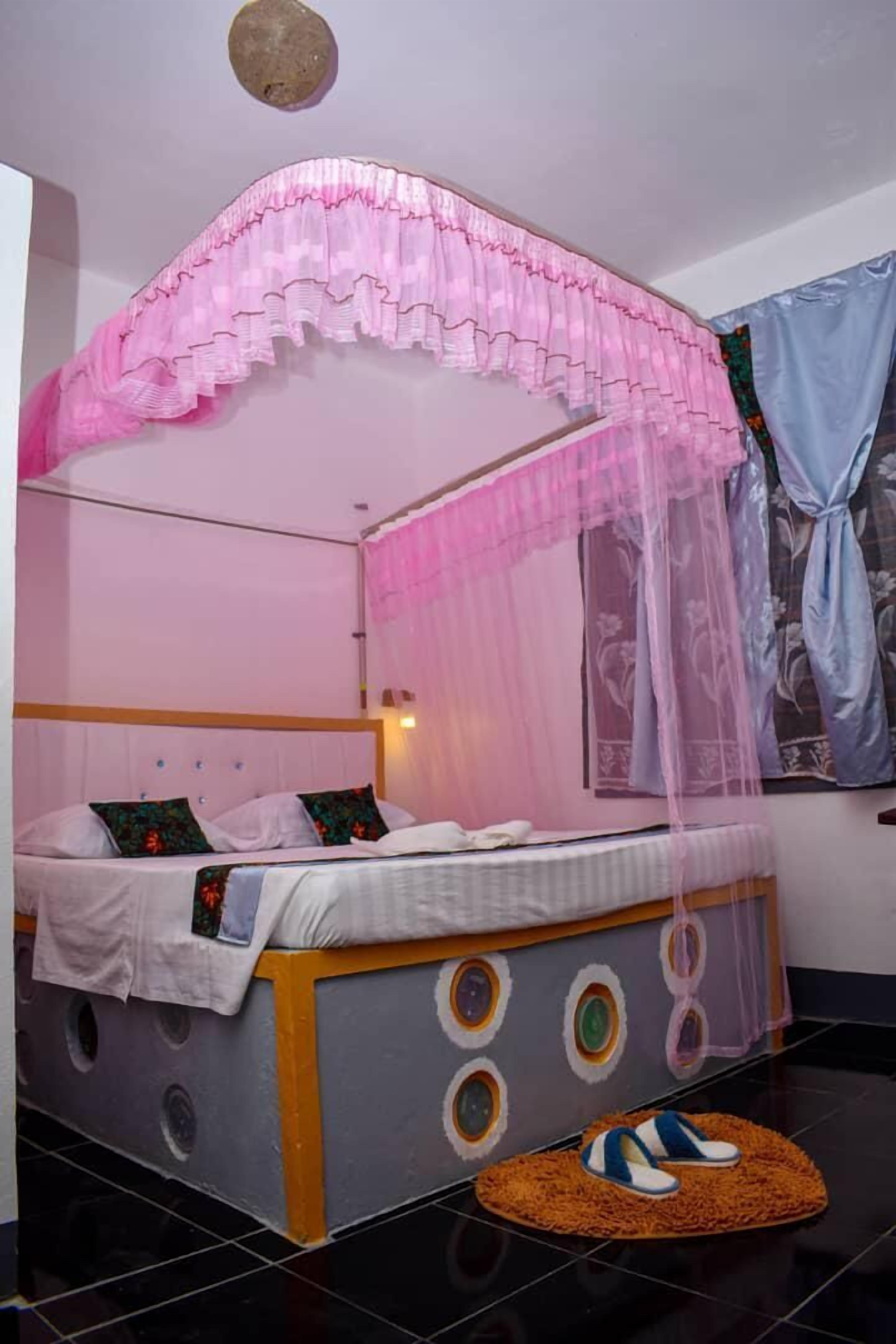 Een bed met hemelbed, een klein vloerkleed en een muur met een rond ontwerp.