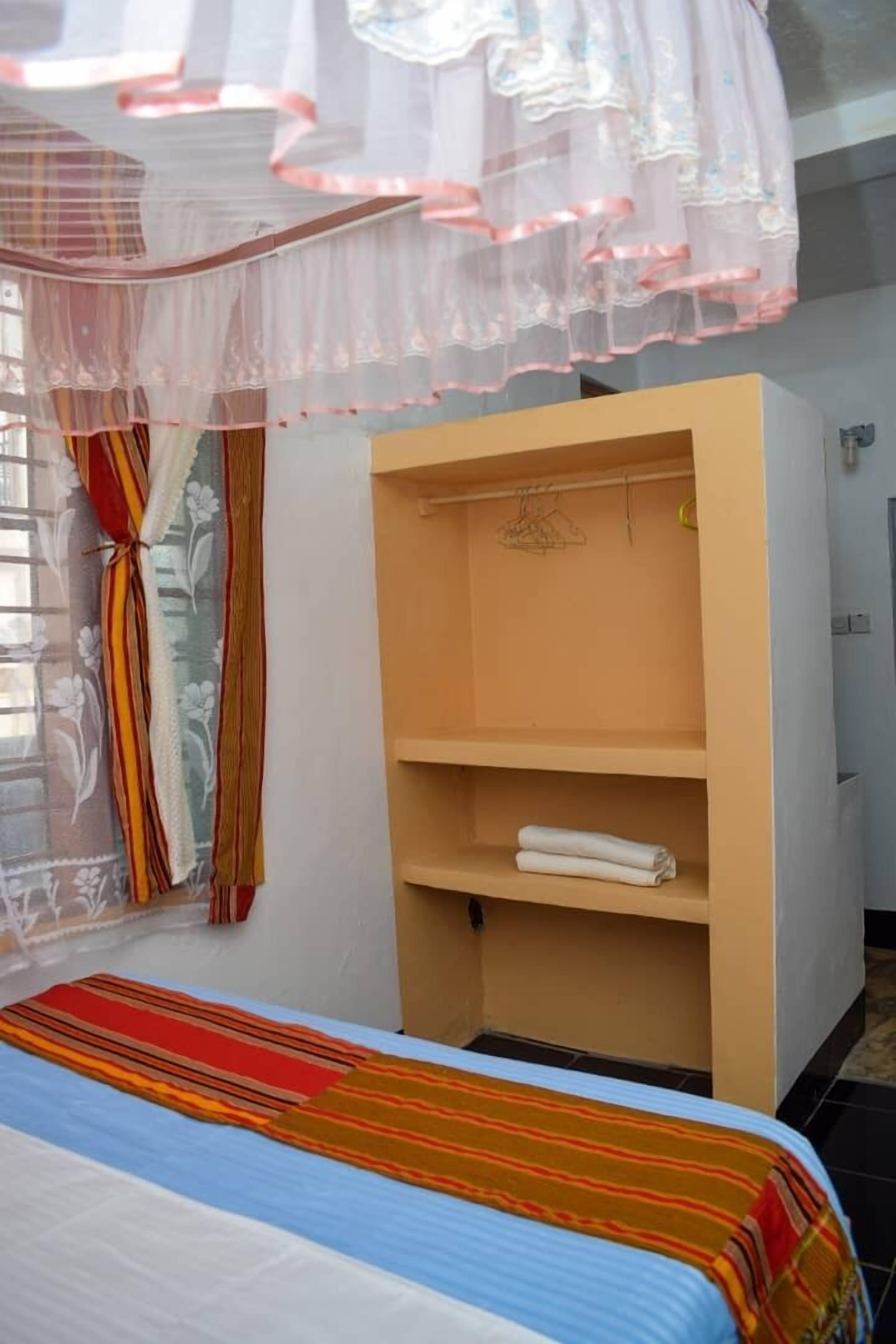 Een slaapkamer met een bed, een kledingkast en een raam met gordijnen.
