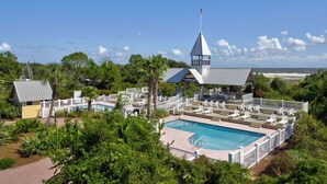 Ein Resort mit Swimmingpool, Liegestühlen und Blick auf den Strand.