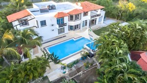 Ein modernes, zweistöckiges Haus mit Swimmingpool, umgeben von üppiger Bepflanzung.