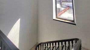 A room with a skylight, a small arched window, and a staircase with a black railing.