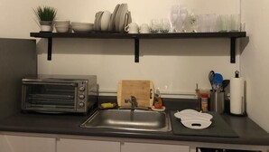 A kitchen with a toaster, sink, and shelves holding dishes and glasses.