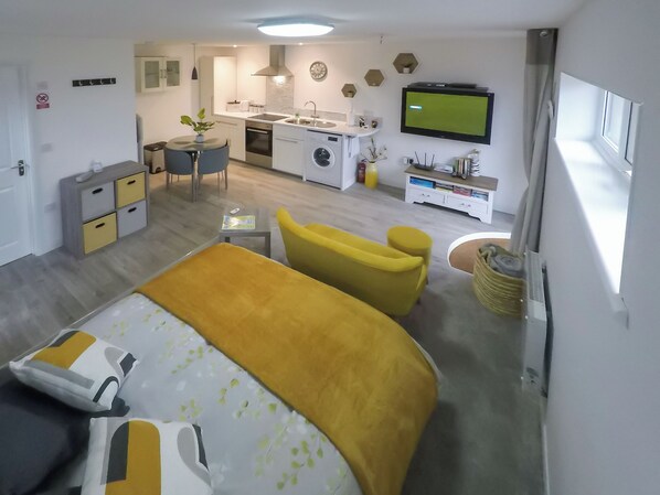 Una habitación de hotel moderna con cama, escritorio, silla, mesita y televisor.