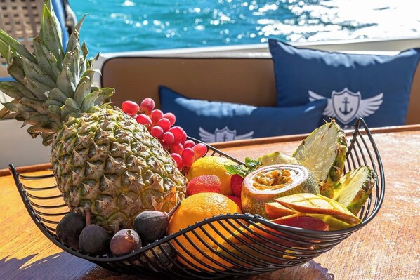 Una cesta de frutas sobre una mesa cerca de una piscina, con vista al agua.