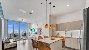 A modern kitchen with a central island, bar stools, and pendant lighting.