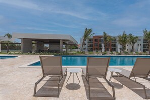 Un espace piscine avec des chaises longues et un coin salon abrité.
