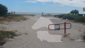 A sandy beach path leading to the sea, with a signpost and a lifeguard tower in the distance. - Apartment with garden - sea view (Palavas-les-Flots)