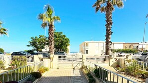 A paved walkway with palm trees, a fence, and parked cars. - Apartment with garden - sea view (Palavas-les-Flots)