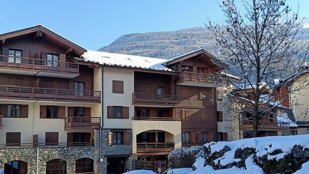 A multi-story hotel with balconies, stone facade, and a snowy landscape.