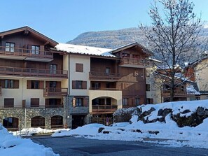 Et hotel med flere etager, altaner, en stenfassade og et sneklædt landskab.