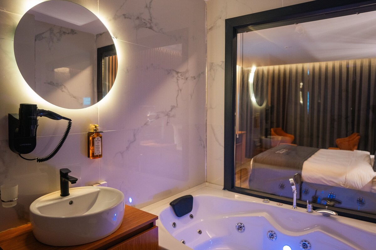 A modern bathroom with a round mirror, a sink, and a large bathtub.