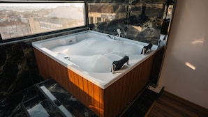 A modern bathroom with a large freestanding bathtub, wooden paneling, and a view of the city through a large window. - Cip hotel istanbul  (Istanbul)