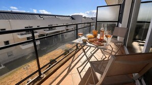A balcony with a table set for a meal, a bottle of wine, and a chair. - Charming love nest with balcony (La Rochelle)