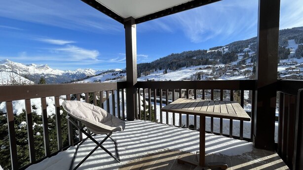 A balcony with a chair and table, overlooking a snowy mountain landscape. - Le Balcon des Princesses (Demi-Quartier)