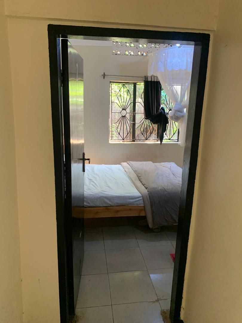 Ein Zimmer mit einem Bett, einem Fenster mit Verzierungen und einem Vorhang.