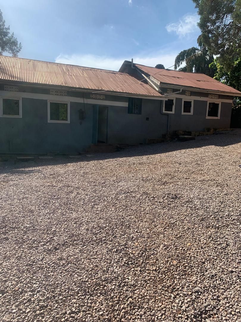 A building with a corrugated metal roof and a gravel driveway.