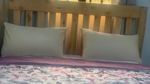 A bed with a floral bedspread, two pillows, and a white headboard. - Watu Guest House (Kampala)