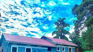 A two-story building with a red roof, surrounded by lush green grass and trees. - Watu Guest House (Kampala)