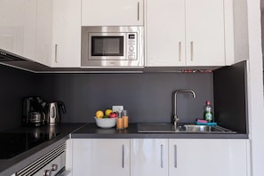A compact kitchen with a microwave, a coffee maker, a sink, and a bowl of fruit. - Apartment in San Eugenio (Costa Adeje)