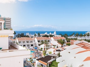Uma área residencial costeira com edifícios brancos, uma piscina e vista para o mar.