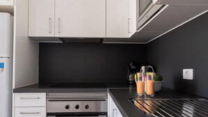 Eine moderne Küche mit weißen Schränken, einem eingebauten Ofen und einer schwarzen Arbeitsplatte.