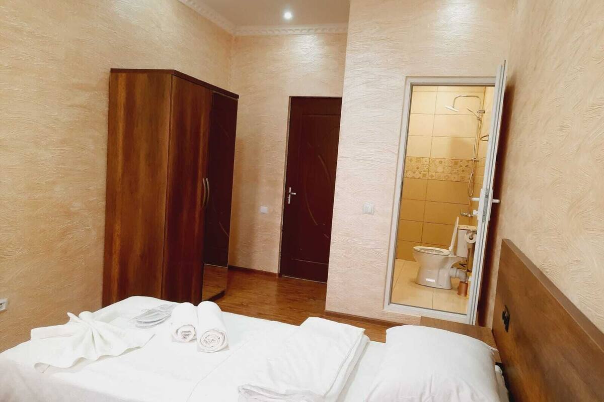 Une chambre d’hôtel avec un lit, une armoire et une salle de bain visible à travers une porte ouverte.