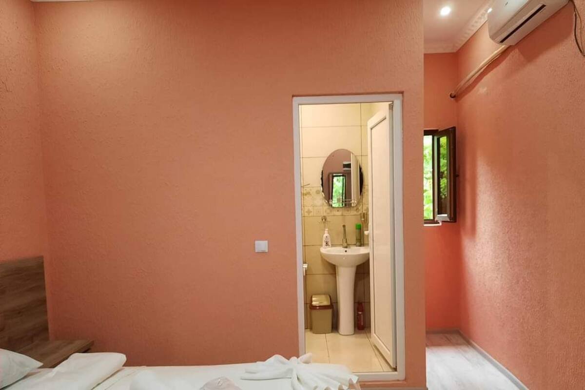 Une chambre à coucher avec un lit, un miroir et une salle de bain visible à travers une porte ouverte.