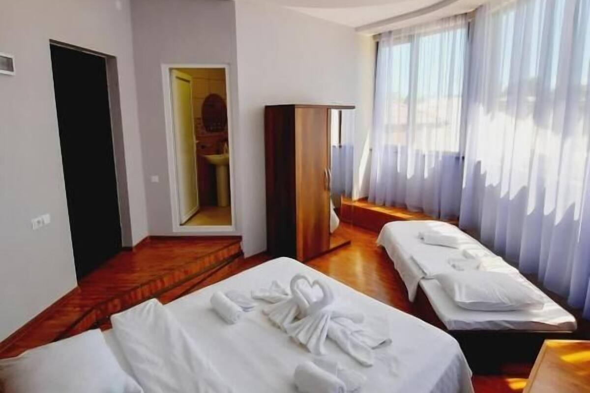 Une chambre d’hôtel avec deux lits, un miroir, une armoire et un luminaire circulaire au plafond.