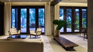 A spacious living room with a sofa, two armchairs, a coffee table, and a large potted plant. - Villa Abrazos (San Pedro)