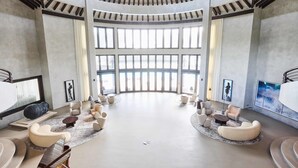 A spacious, modern lobby with a high ceiling, large windows, and a central seating area with sofas and a coffee table. - Villa Abrazos (San Pedro)