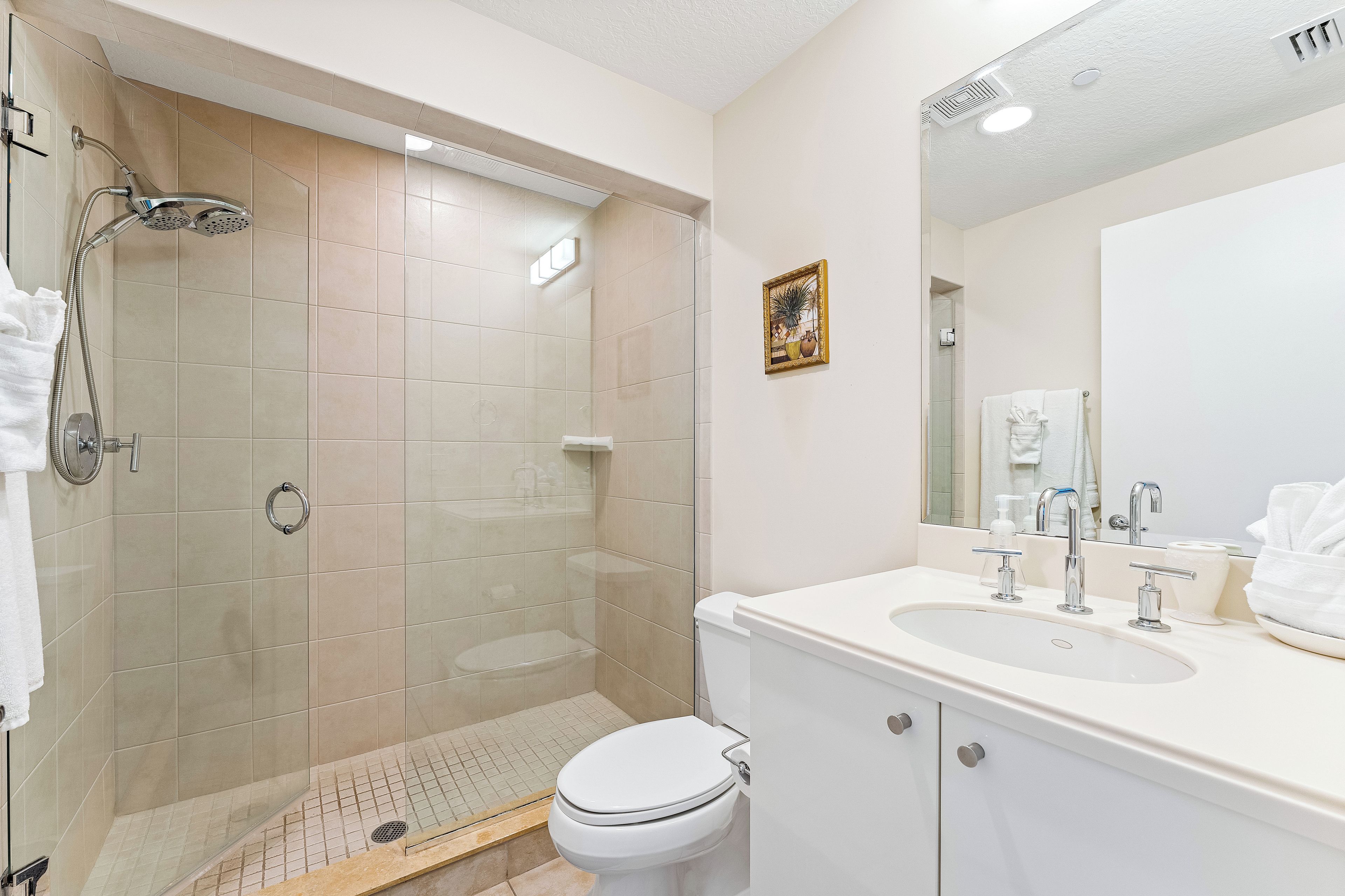 Une salle de bain moderne avec une douche à parois de verre, des toilettes et un lavabo avec un miroir au-dessus.
