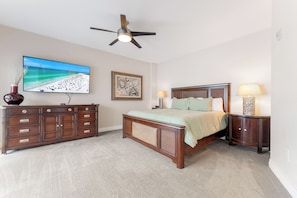 A bedroom with a bed, a dresser, a television, and a ceiling fan. - Crescent Condos by Beachside Management (Siesta Key)