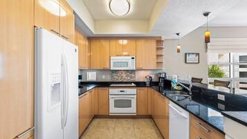 A modern kitchen with wooden cabinets, a white refrigerator, a microwave, and a built-in oven.