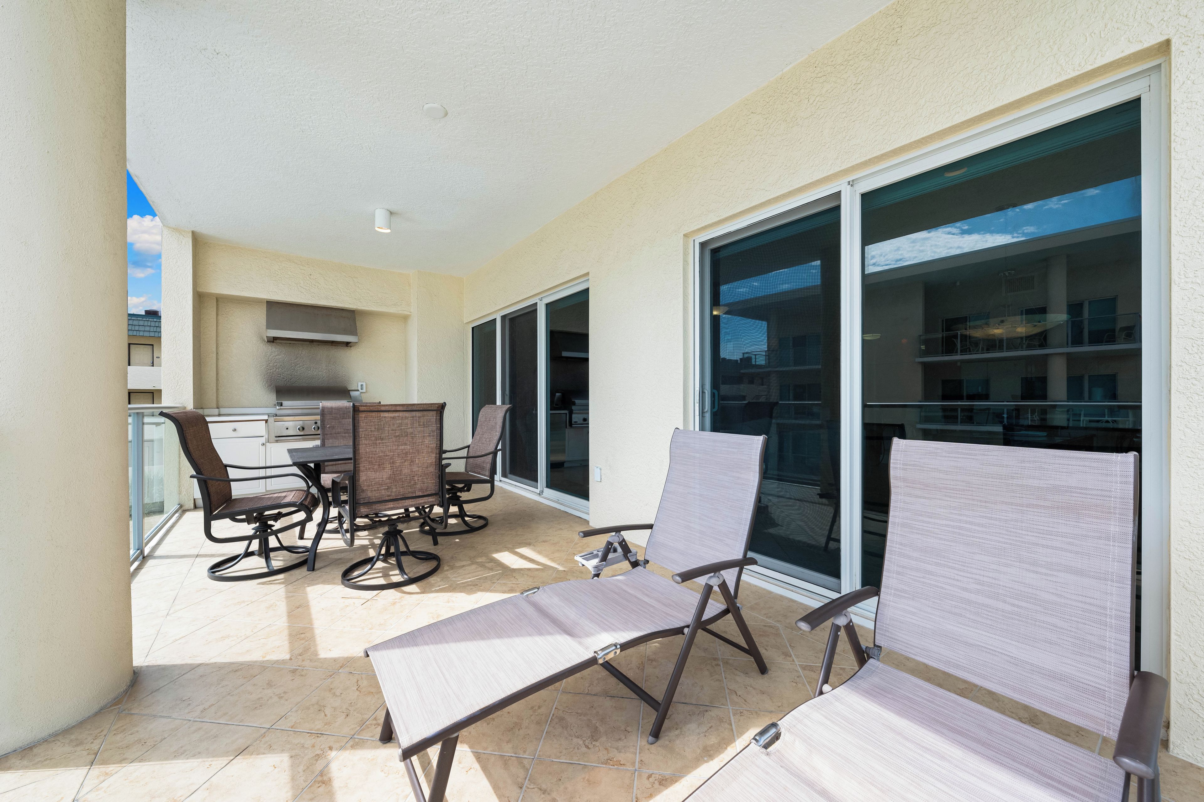 A balcony with a dining table and chairs, a sliding glass door, and a view of a building.